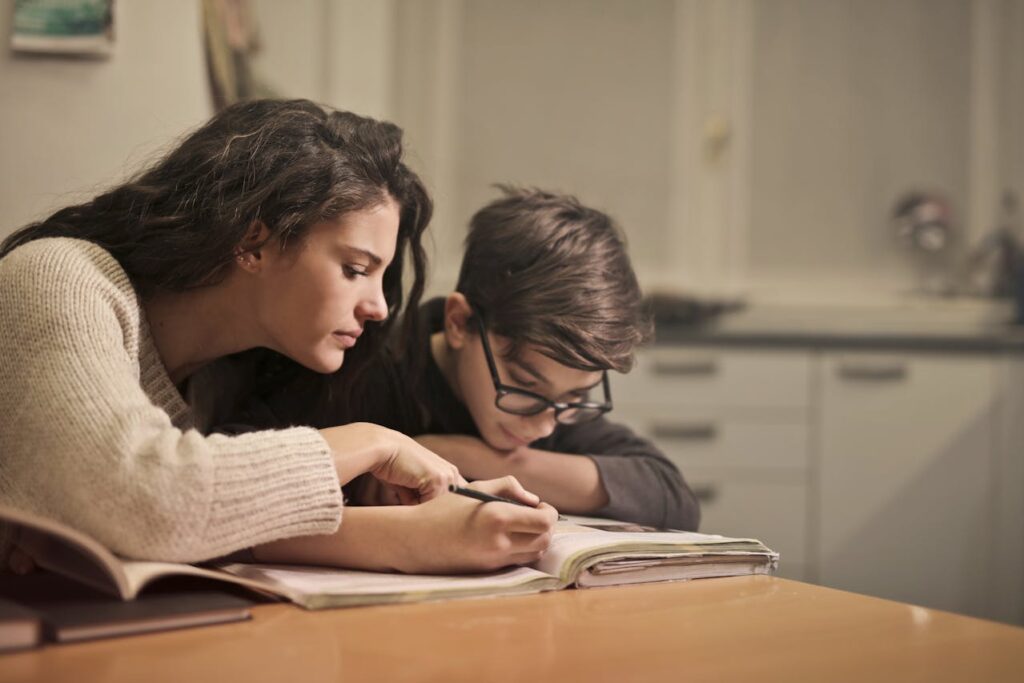 A mother helping her son with his schoolwork at the kitchen table